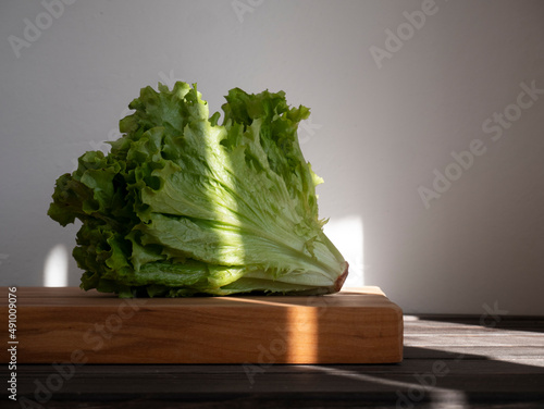 lettuce on wooden cutting board, still life photography elegant light shadow contrast with thin vertical light beam, elegant and modern rustic food photo