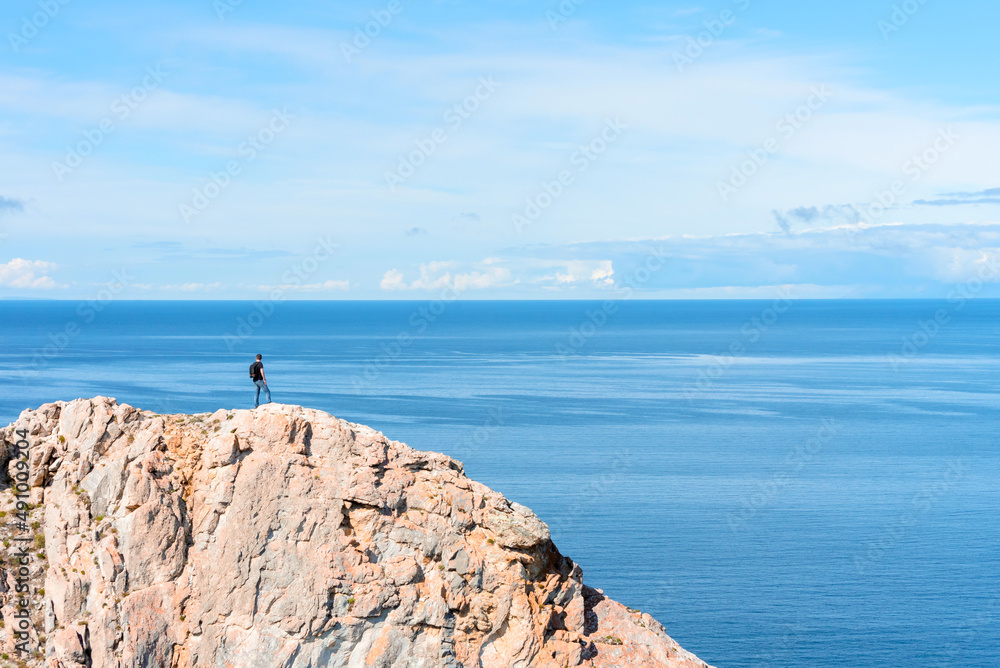 Man standing on a rock at the end of earth. Hiking or travel concept. Explore the great outdoors. Beauty of nature Man standing on a rock at the end of earth. Hiking or travel concept. Explore the great outdoors. Beauty of nature
