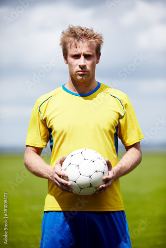 I wont settle for less than a win. Shot of a determined looking soccer player holding a soccer ball outdoors. © M S/peopleimages.com