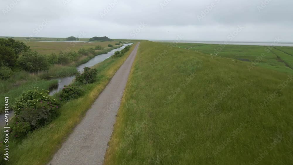 The lonely road in the countryside with the river on one side and the sea on the other. The video is filmed by drone with constant speed. Cloudy weather is adding to the moody feeling of the clip. The lonely road in the countryside with the river on one side and the sea on the other. The video is filmed by drone with constant speed. Cloudy weather is adding to the moody feeling of the clip.