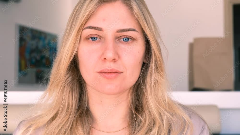 Confident young beautiful blue-eyed blonde woman without makeup looks into the camera. Morning portrait of a girl. Slow motion, 4k Confident young beautiful blue-eyed blonde woman without makeup looks into the camera. Morning portrait of a girl. Slow motion, 4k