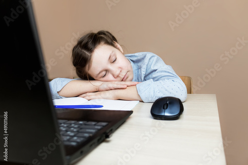 the girl fell a sleep sitting at the table during an online lesson and from fatigue at the laptop.