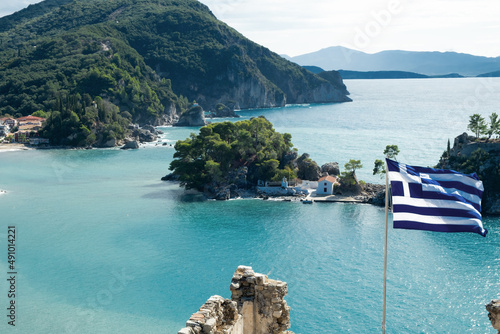 National Greek flag flying on background of beautiful seaview, Parga bay, mountains, turquoise sea in sunny weather.Travel to Greece,picturesque seascape concept.View from top, fortress photo