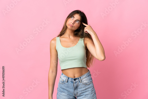 Young caucasian woman isolated on pink background making the gesture of madness putting finger on the head