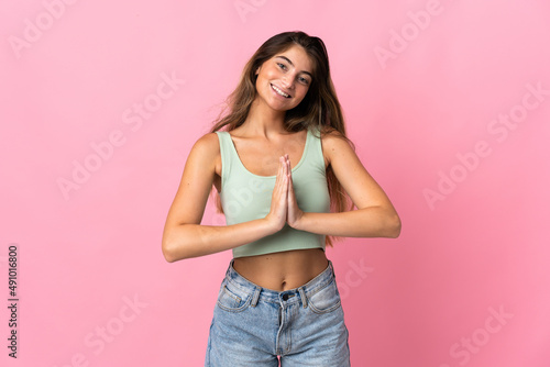 Young caucasian woman isolated on pink background keeps palm together. Person asks for something