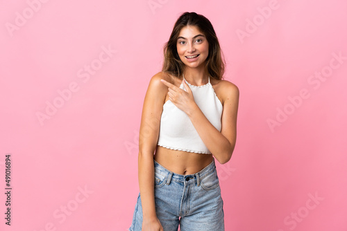 Young caucasian woman isolated on pink background pointing to the side to present a product © luismolinero