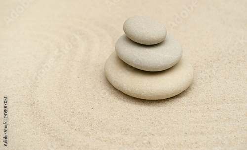 Zen stones garden. Pyramids of gray zen stones on the white sand with abstract blur wave. Concept of purity, harmony, balance and meditation, spa, massage, relax.