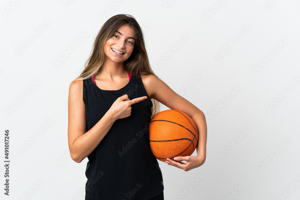 Young caucasian woman isolated on white background playing basketball and pointing to the lateral Young caucasian woman isolated on white background playing basketball and pointing to the lateral
