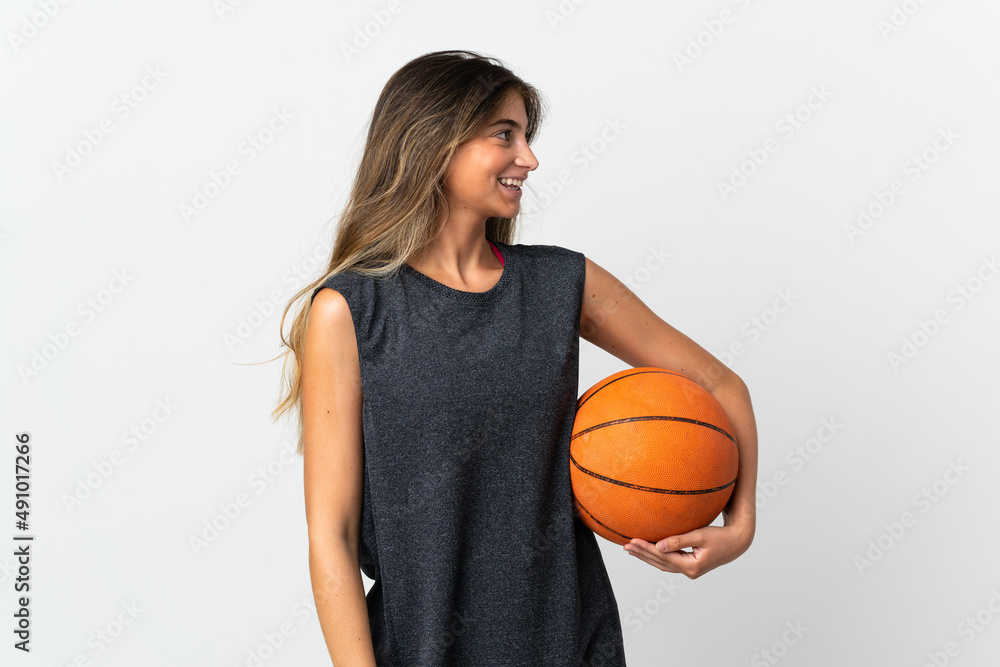 Young woman playing basketball isolated on white background looking side