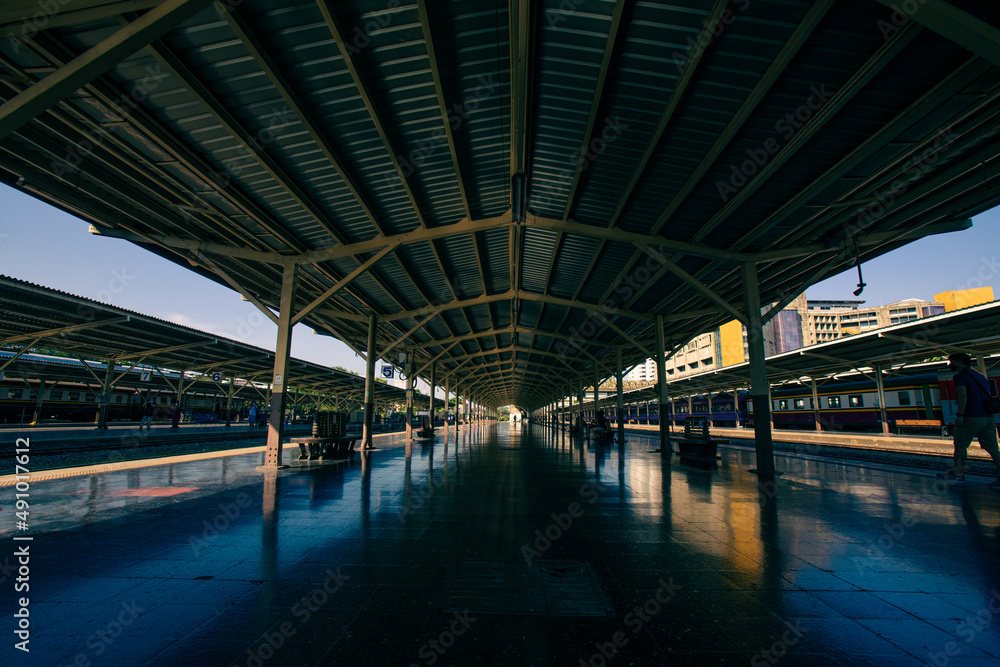 Perspective railway station platform under a steel frame roof