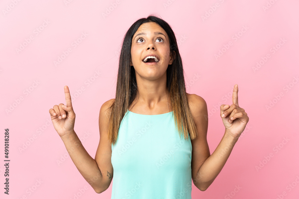 Caucasian girl isolated on pink background surprised and pointing up Caucasian girl isolated on pink background surprised and pointing up
