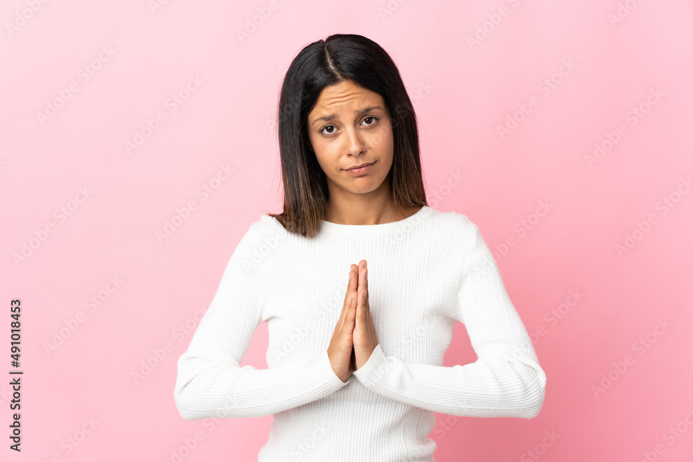 Caucasian girl isolated on pink background keeps palm together. Person asks for something Caucasian girl isolated on pink background keeps palm together. Person asks for something