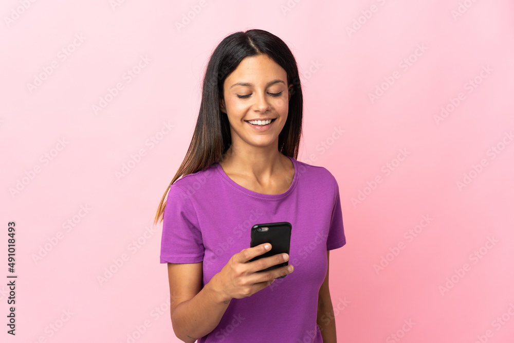 Caucasian girl isolated on pink background sending a message or email with the mobile Caucasian girl isolated on pink background sending a message or email with the mobile