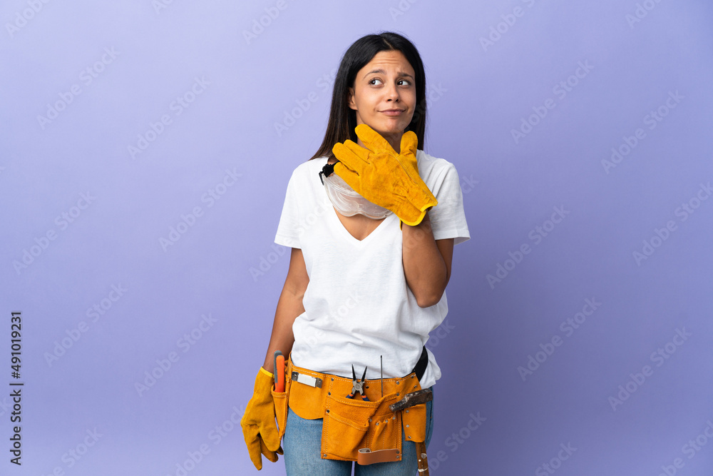 Young electrician woman isolated on purple background having doubts Young electrician woman isolated on purple background having doubts