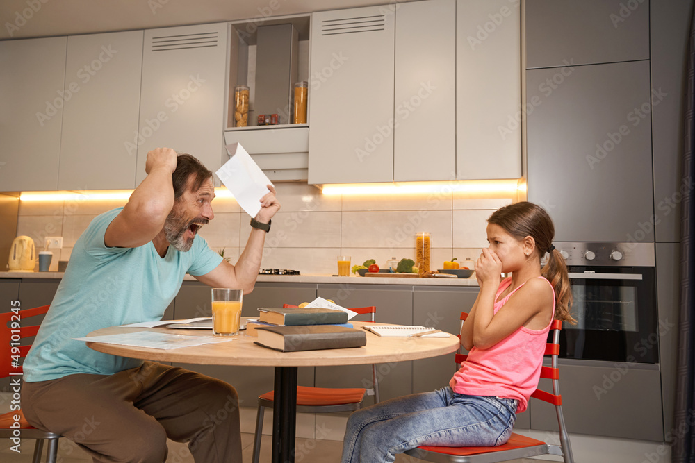 Man is yelling at girl at kitchen table Man is yelling at girl at kitchen table