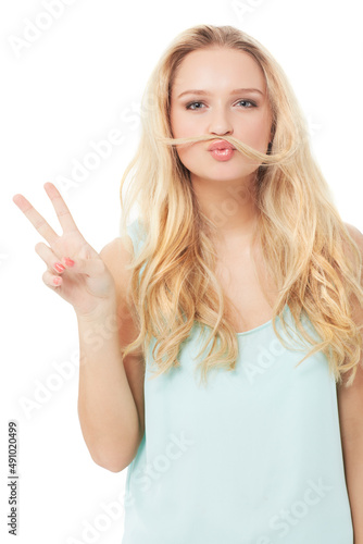 Give peace a chance. A quirky young blonde showing you a peace sign with her hair over her mouth - isolated.