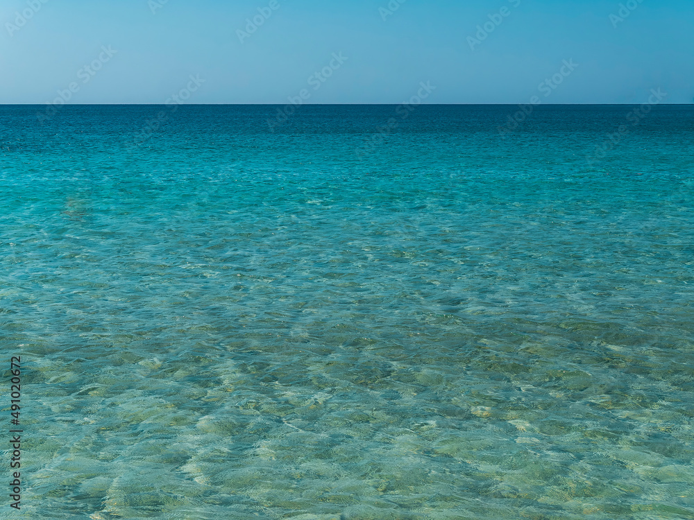 Smooth sea waves blue pattern under crystal clear light blue sky