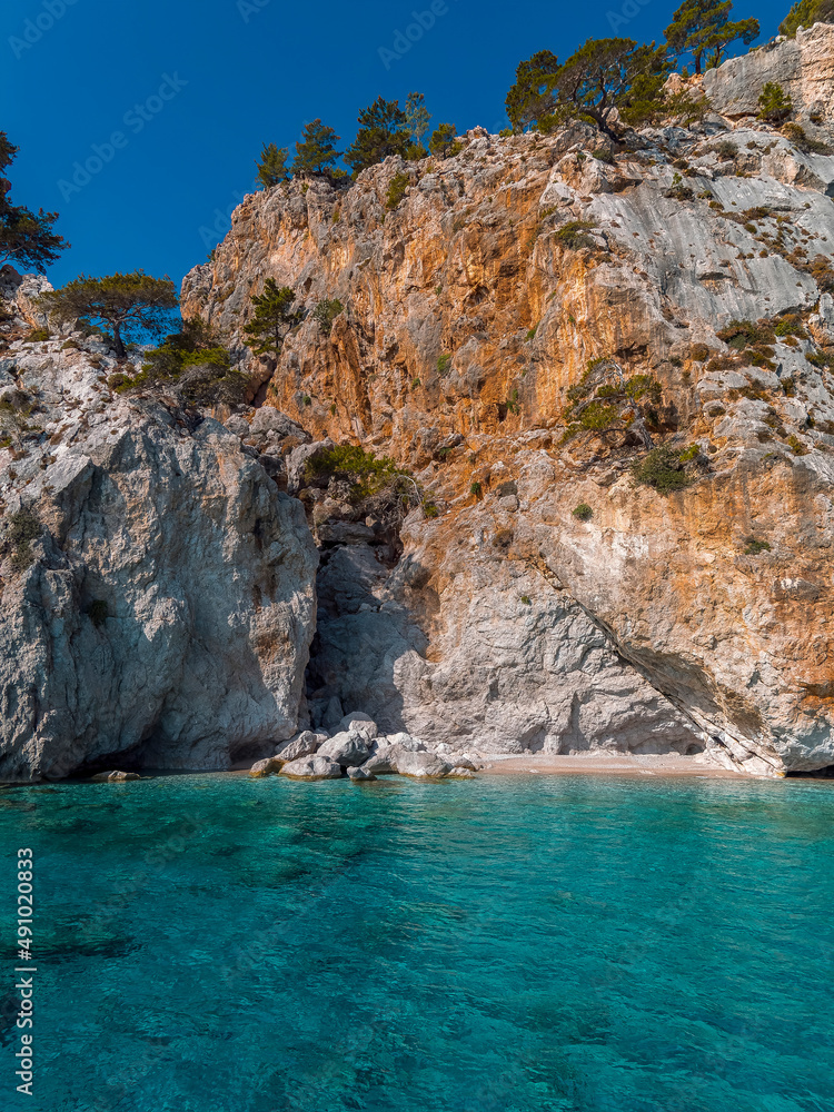 Transparent sea water and a tiny beach under impressive rocks, Karpathos island, Greece.
