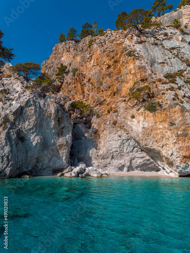 Transparent sea water and a tiny beach under impressive rocks, Karpathos island, Greece. © Dimitrios
