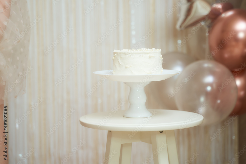 White birthday cake with balloons on the background