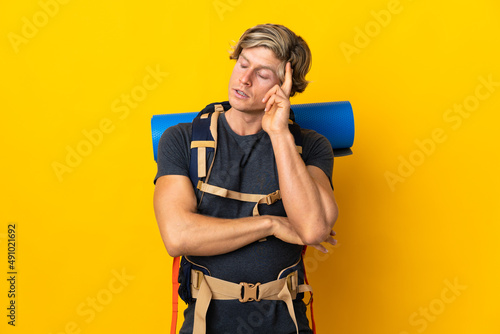Young mountaineer man over isolated yellow background with headache