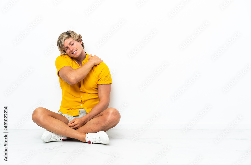 Fototapeta premium Young English man sitting on the floor suffering from pain in shoulder for having made an effort