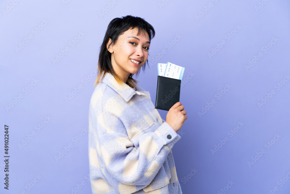 Young Uruguayan woman over isolated purple background happy in vacation with passport and plane tickets Young Uruguayan woman over isolated purple background happy in vacation with passport and plane tickets