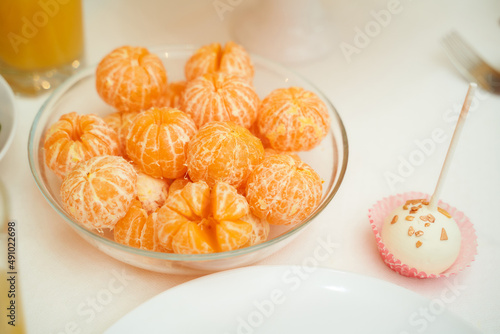Delicious peeled tangerine slices lie in a transparent plate with desserts