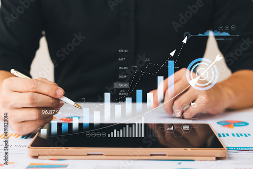 Businessman analyzing company's financial balance sheet working with digital augmented reality graphics. Businessman calculates financial data for long-term investment. photo