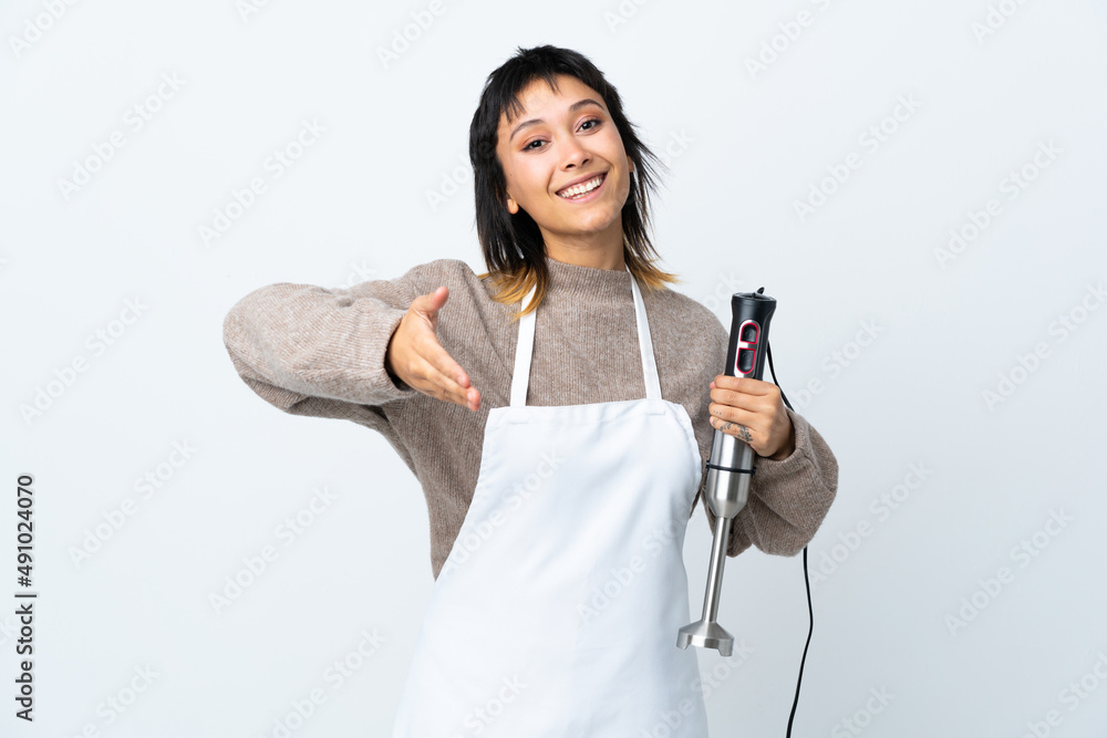 Chef Uruguayan girl using hand blender over isolated white background handshaking after good deal Chef Uruguayan girl using hand blender over isolated white background handshaking after good deal