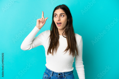 Young caucasian woman isolated on blue background intending to realizes the solution while lifting a finger up