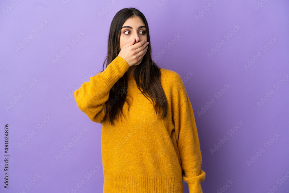 Young caucasian woman isolated on purple background doing surprise gesture while looking to the side Young caucasian woman isolated on purple background doing surprise gesture while looking to the side