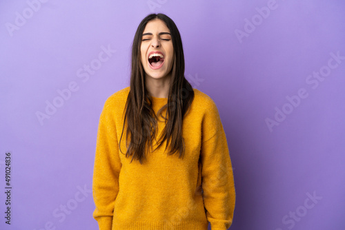 Young caucasian woman isolated on purple background shouting to the front with mouth wide open © luismolinero