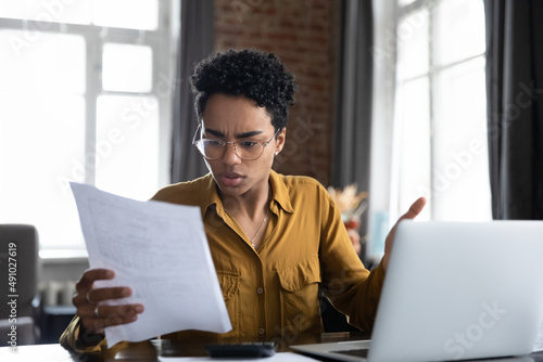 Worried frustrated Black professional woman reading paper notification with bad news, getting problems, dismissal, bankruptcy. Student girl receiving document from college, rejection notice