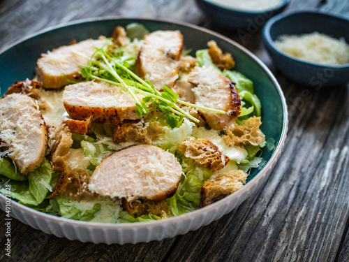 Caesar salad - fried chicken breast and vegetables on wooden table