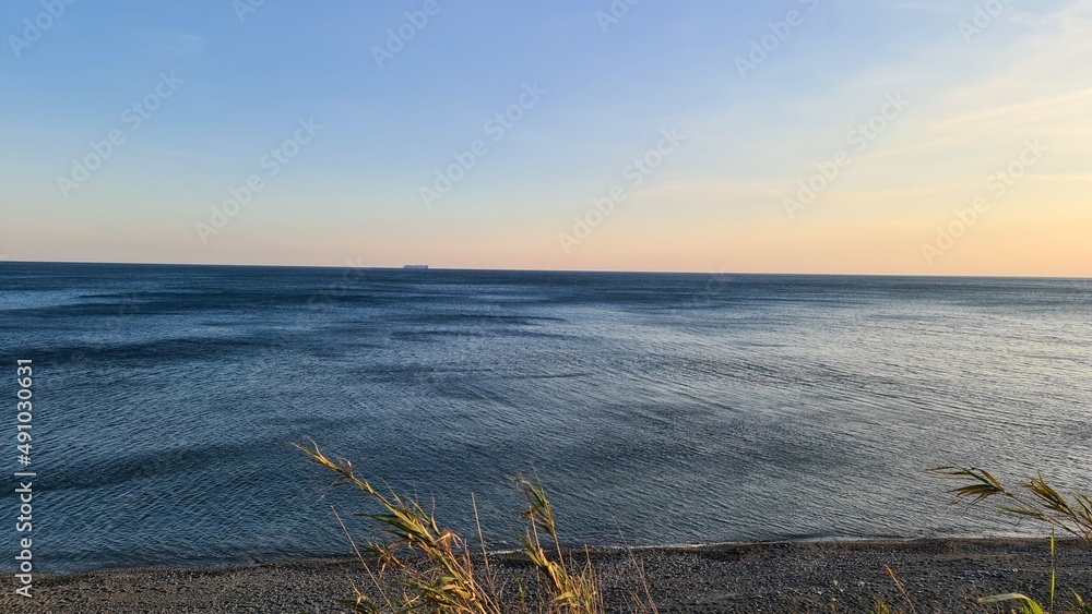 Savona, Italy - February 12, 2022: Panorama of the sea sunset, light above the water, ocean sunrise. Some little waves in winter days.