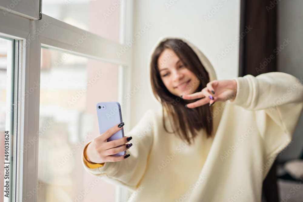 Happy female blogger taking selfie portrait on smartphone camera for social media posting, cheerful teenage girl talking on video call with family or friends via mobile phone.Soft selective focus. Happy female blogger taking selfie portrait on smartphone camera for social media posting, cheerful teenage girl talking on video call with family or friends via mobile phone.Soft selective focus.