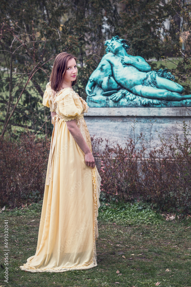 young woman outdoors in historical yellow dress