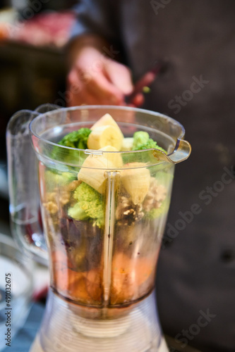 Banana broccoli and different types of fruits in the blender to make a healthy juice