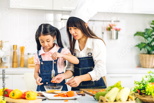 Portrait of enjoy happy love asian family mother and little asian girl daughter child having fun help cooking food healthy eat together with fresh vegetable salad and sandwich ingredient in kitchen