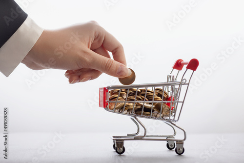 online commerce and banking concept, businessman's hand stacks coins in supermarket trolley, cashback background photo