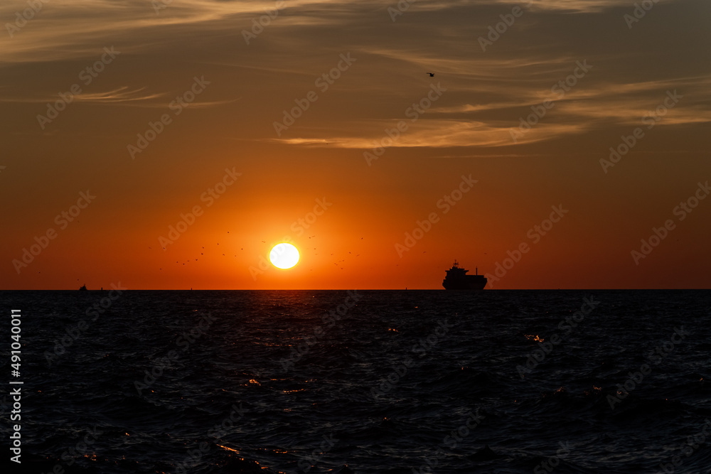 The silhouette of the ship on the horizon, going into the sunset.