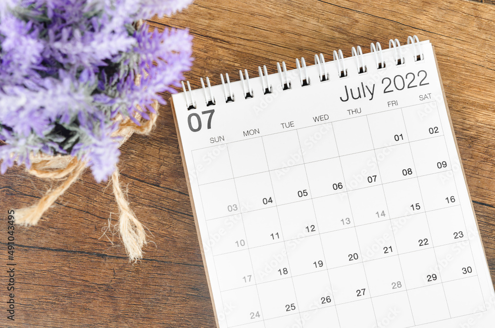 July 2022 desk calendar with flower on wooden background. July 2022 desk calendar with flower on wooden background.