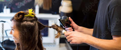 Woman getting new hairstyle done by hairdresser in the modern hair salon.