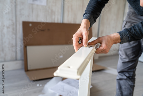 One man unknown caucasian male sitting on the floor at home Putting Together Self Assembly Furniture diy assembly holding parts and instructions real people copy space focus on hands