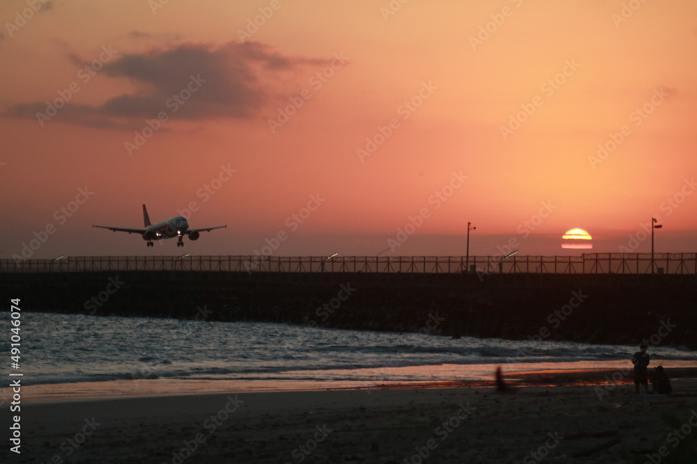 the plane lands at the Ngurah Rai airport in Bali at sunset