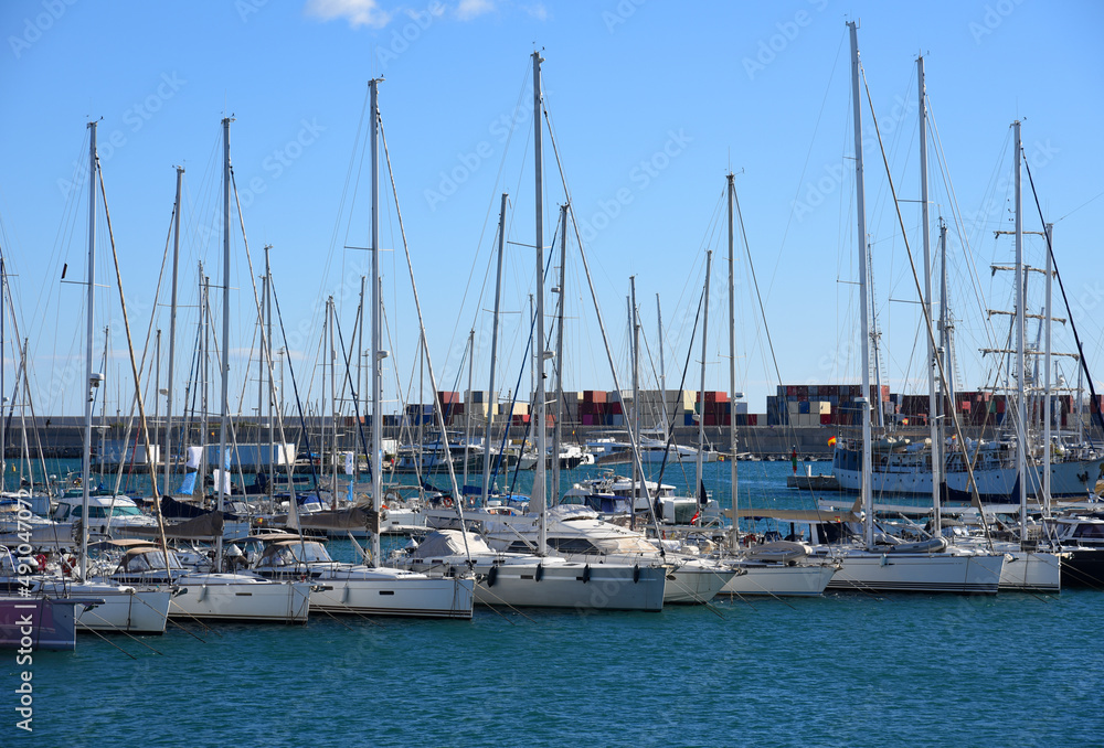 Yachts and motor boats in La Marina de Valencia, Spain. Luxury yacht and fishing motorboat in yacht club at Mediterranean Sea. Skiff and Sailboat in port. Yachting and sailing sport. Quai at ​Dock