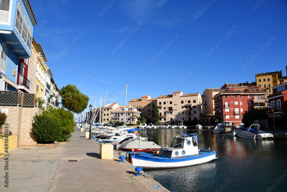 Yachts and motor boats in marina Port Saplaya, Valencia, Alboraya, Spain. Luxury yacht and fishing motorboat in yacht club on background of the colourful houses at Mediterranean Sea. Sailboat port.