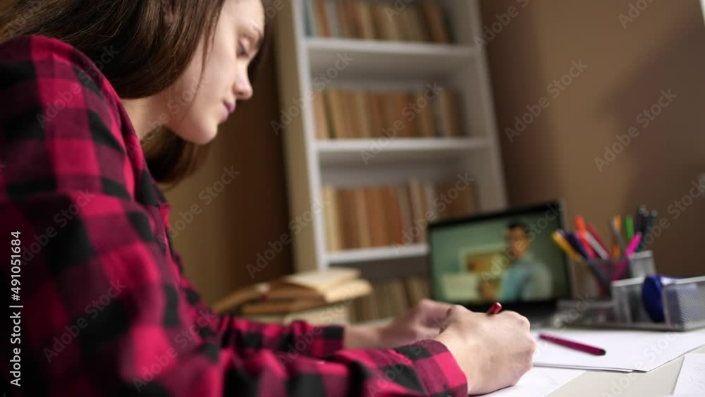 student online learning. girl teenager studies at home school remotely through a laptop in a room next to a bookcase. distance learning education school concept. consultation education indoor student online learning. girl teenager studies at home school remotely through a laptop in a room next to a bookcase. distance learning education school concept. consultation education indoor