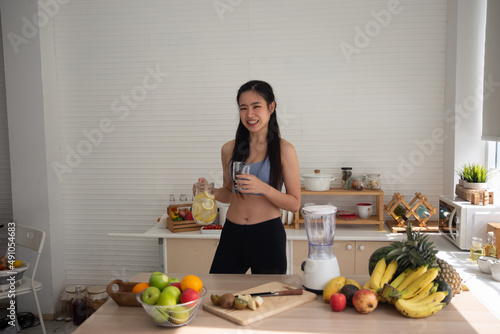 young Asian woman cooking vegetable healthy food and eating or drinking in home kitchen